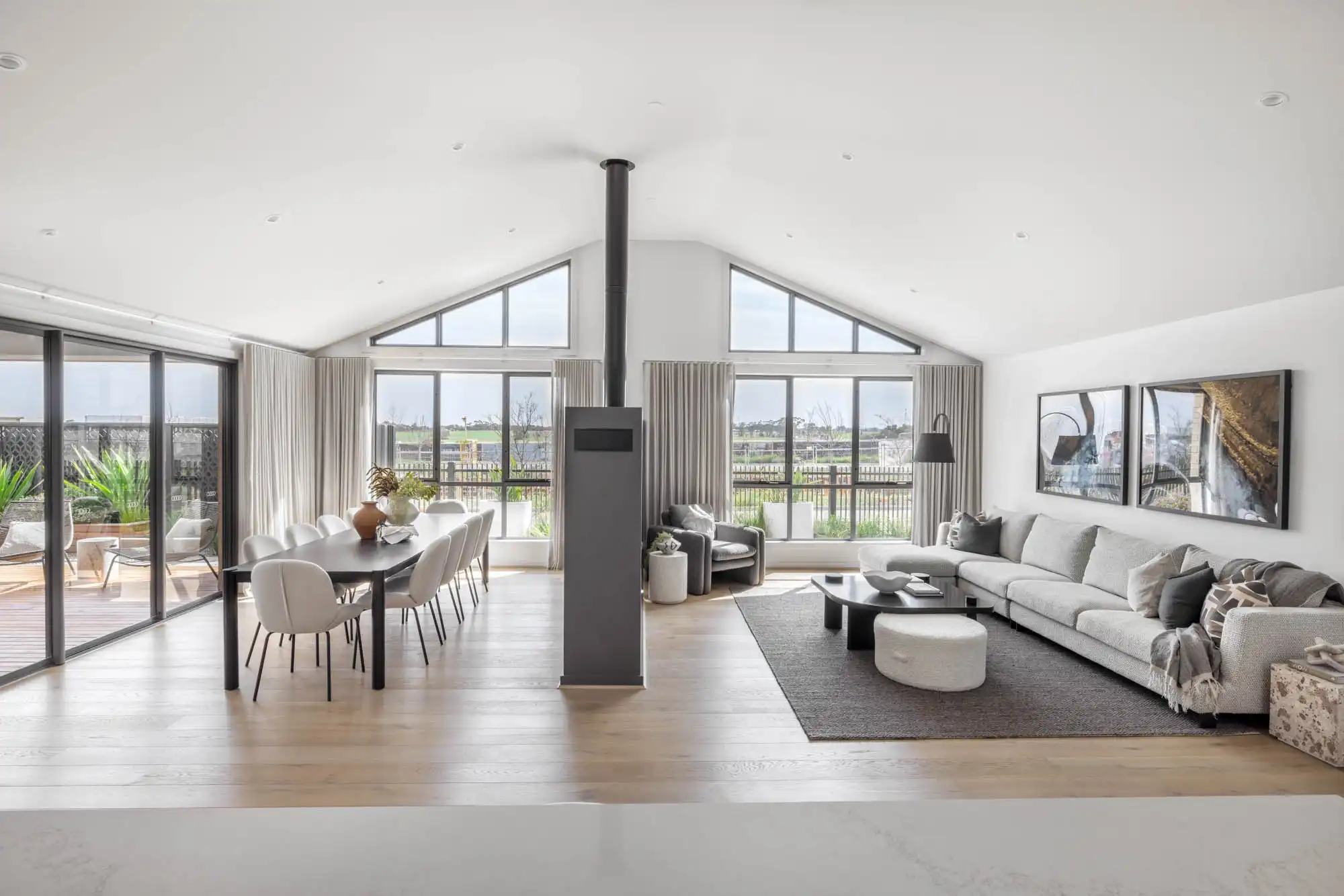 raked ceiling and high windows in an open plan living space with fireplace centered of the room