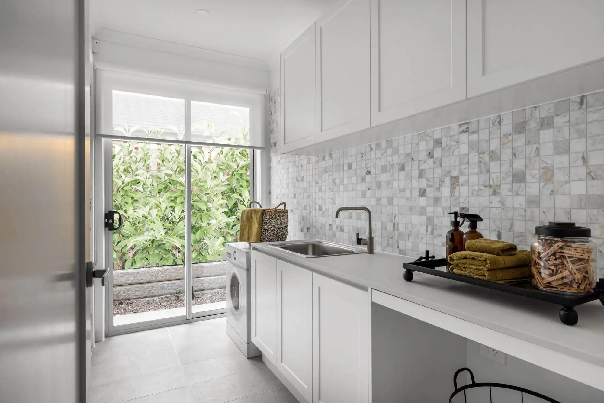 grid stacked marble tiling laundry design includes a sliding door for easy access at riverway 26