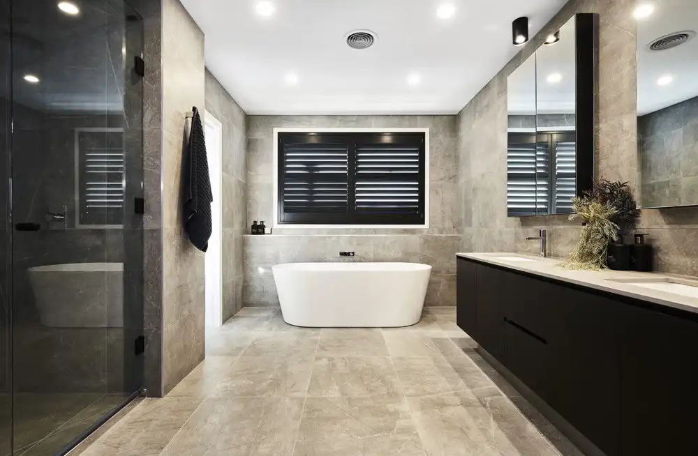 light-toned stone tiling in master ensuite with freestanding bath and dark cabinetry at tallowood 52