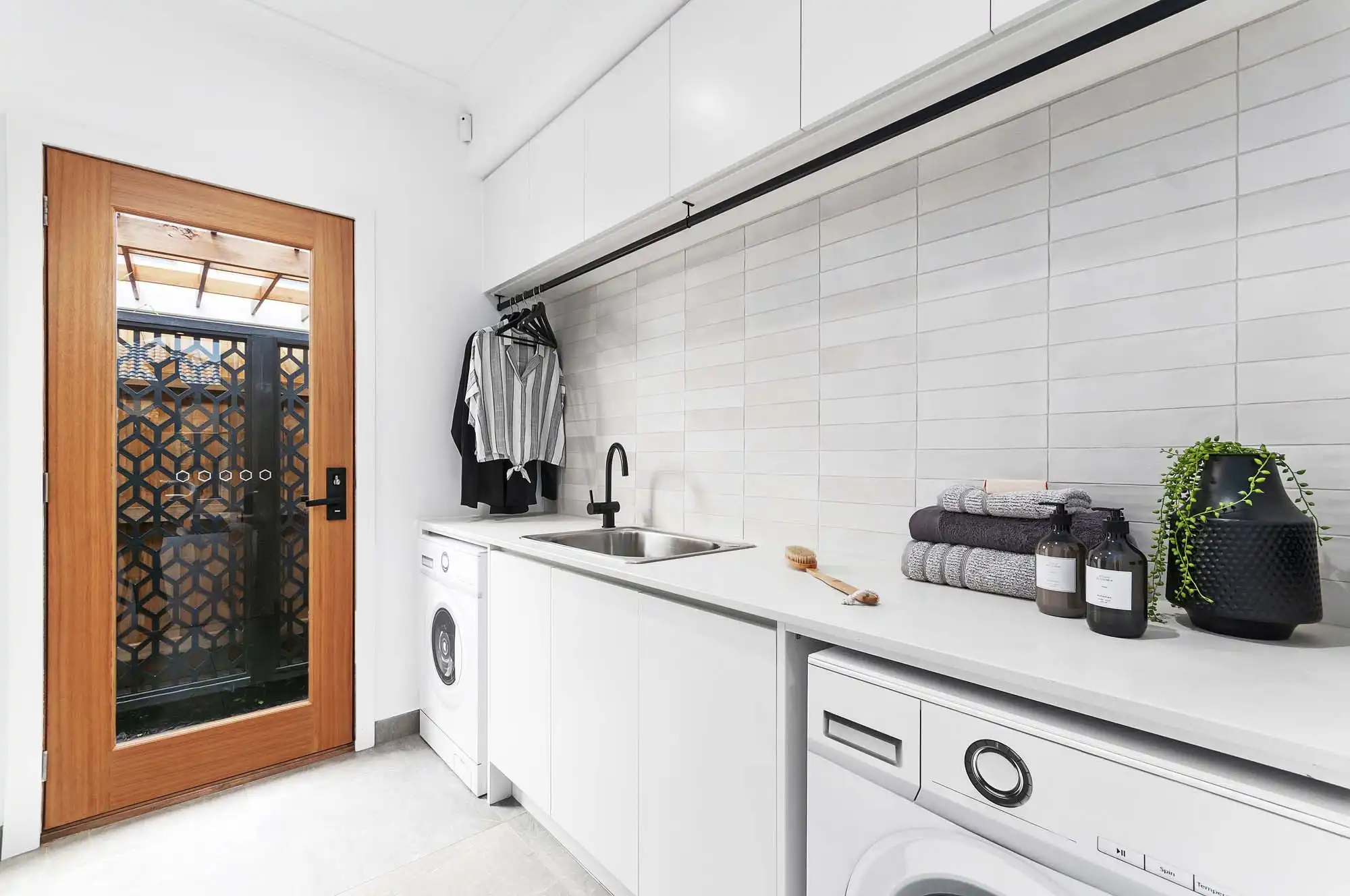 light coastal grid stacked tiling in laundry with large wooden door to brighten up this tamworth 32