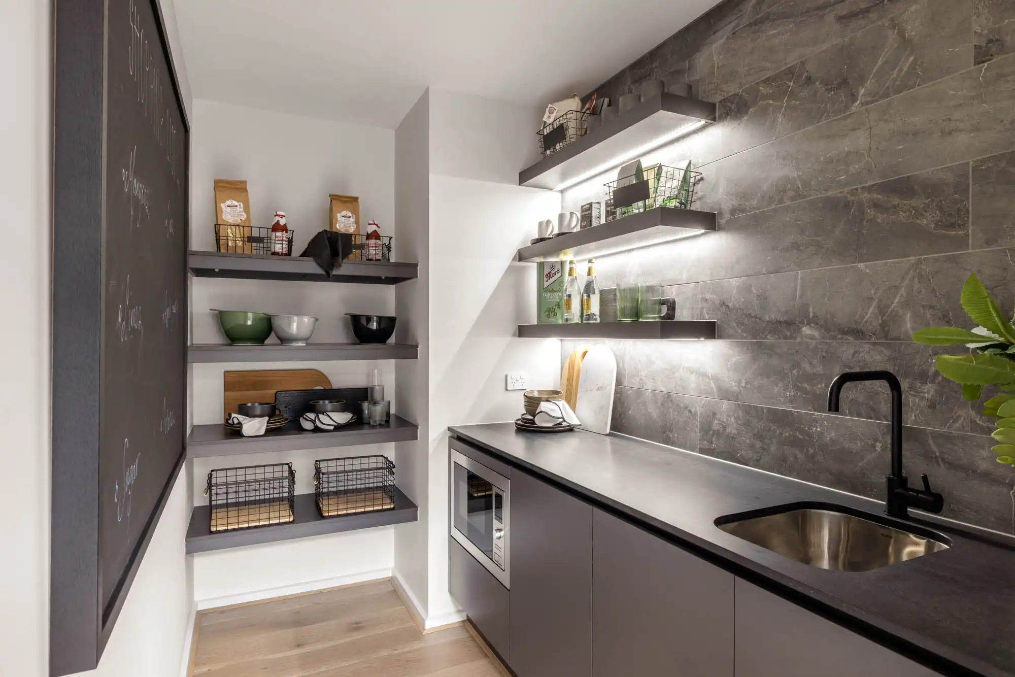 stone-like staggered tiling in grey dark cabinetry with lighting placed beneath the shelving to brighten up the pantry at armidale 34