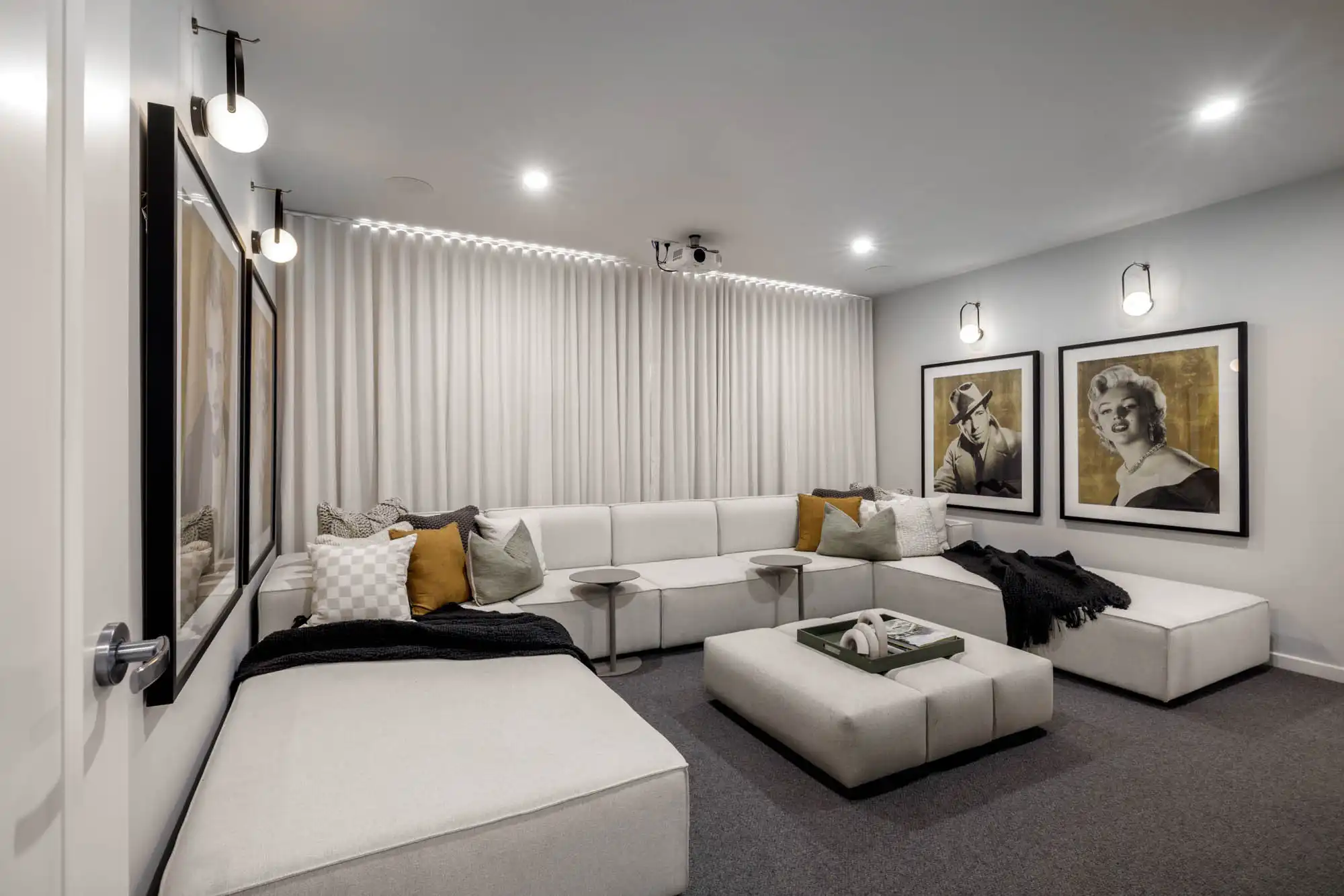 Interior photo of a home cinema with a light grey couch which matches the light grey curtains, as part of the Simonds double storey Tallowood 52 new home design in Fyansford, Geelong featuring block out curtains in the home theatre
