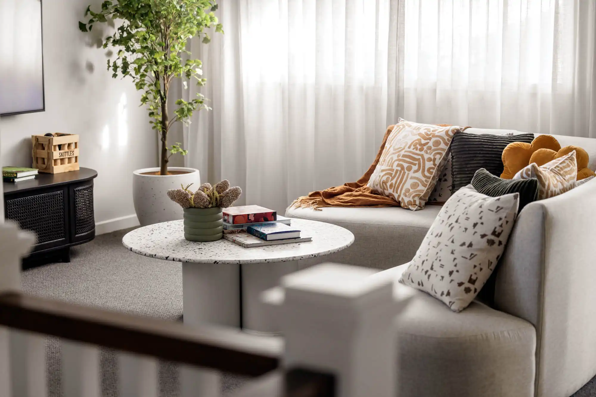 a cosy interior living space with neutral coloured sofa textured pillows and natural light at tallowood 52