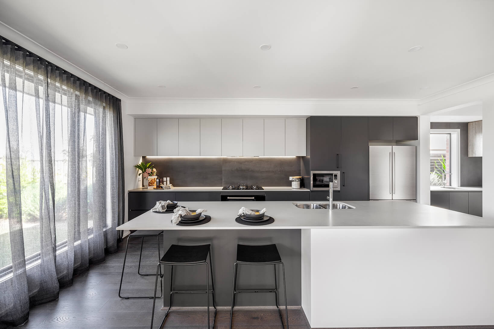 An interior image of a modern open kitchen with a large sliding window overlooking the garden as part of Simonds Berwick home design.