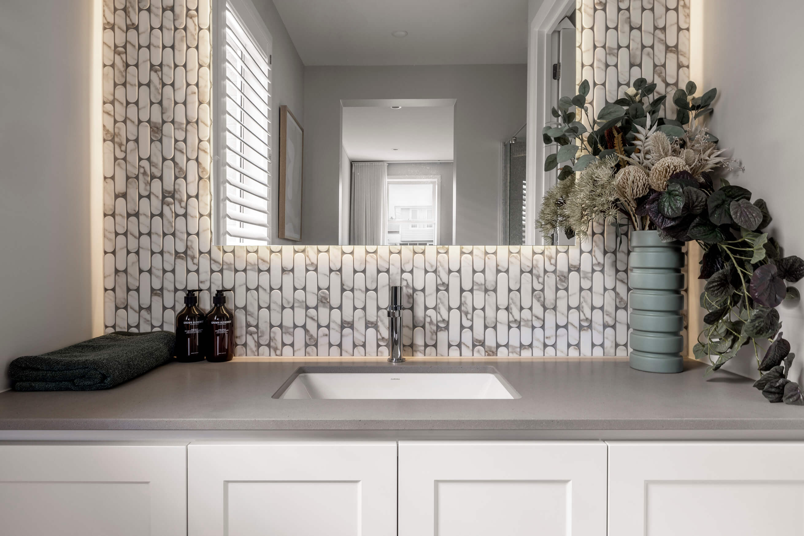 Photo of a bathroom basin with marble textured mosaic tiling around the mirror in the Simonds Tallowood 52 home design