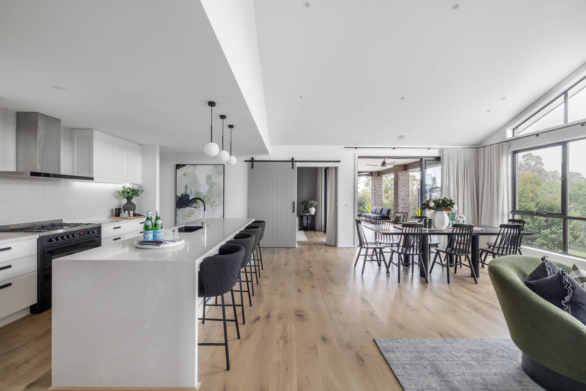 Barn timber sliding door as a feature of this open plan living space at the Redhill 30 with monochromatic style throughout the space