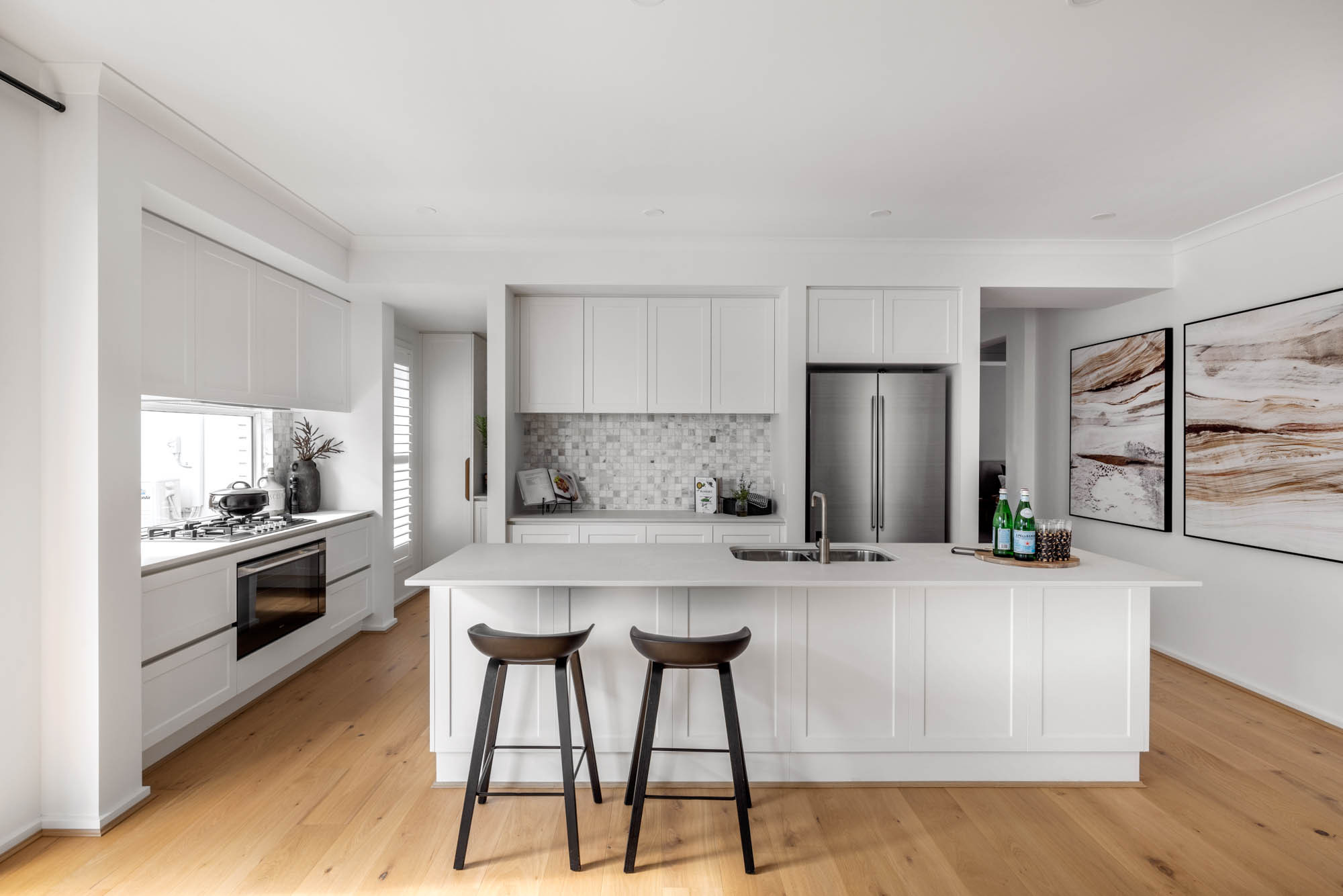 An image of an open living kitchen with wooden flooring that blends modern living as part of Simonds Riverway 26 home design.