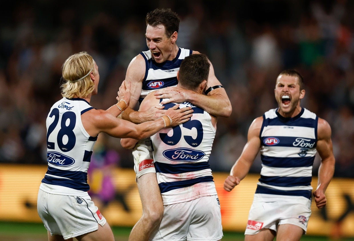 Geelong players hugging and celebrating a goal.