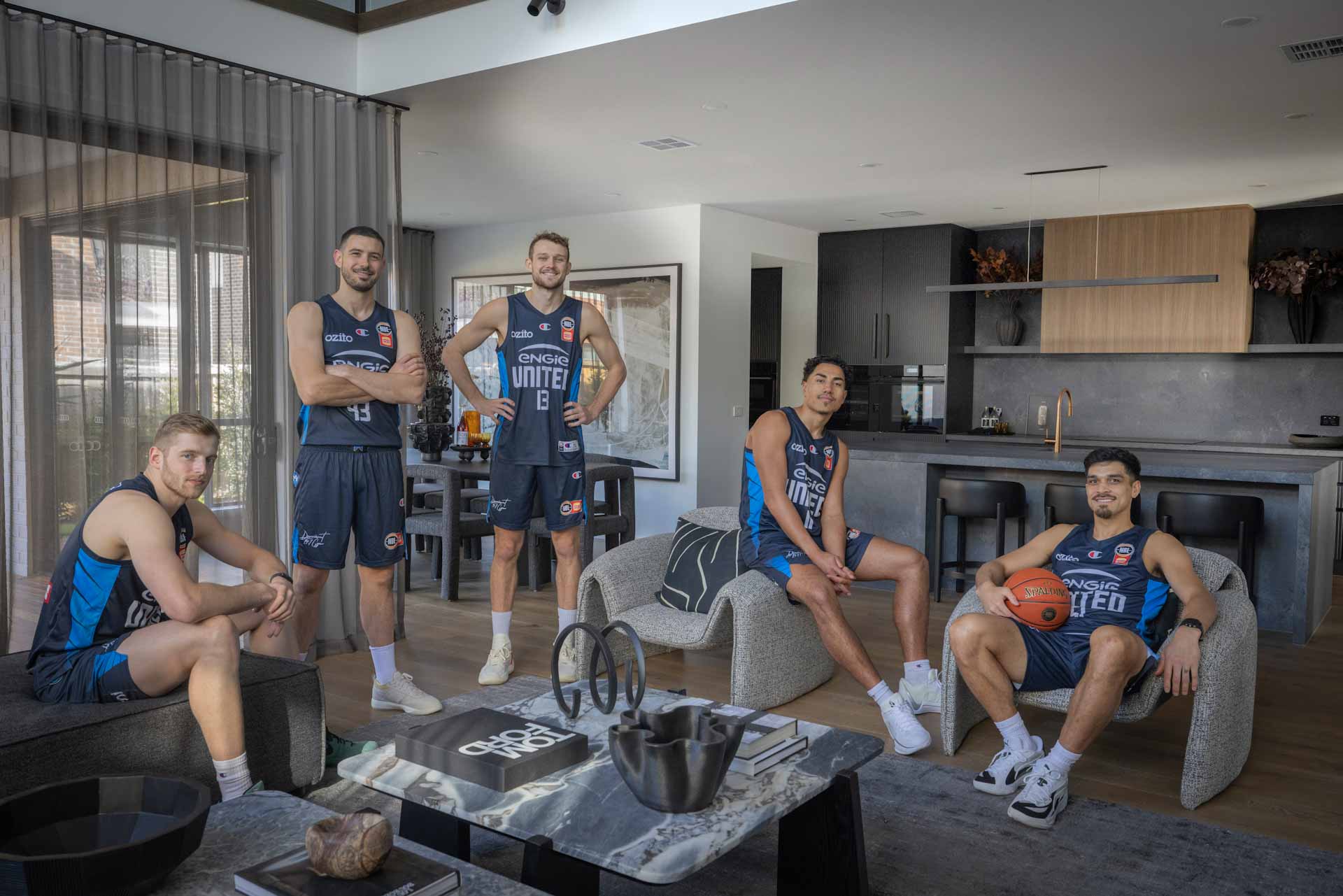 5 Melbourne United players sitting in the living room of the Tallowood 52 on display at Berwick Waters