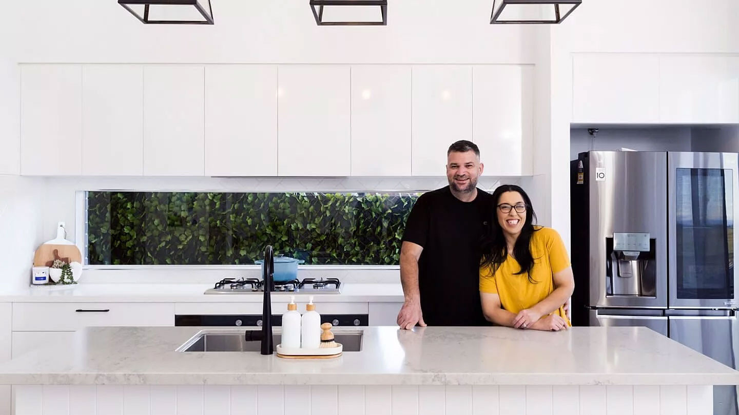 Interior photo of a couple smiling in their open-concept kitchen.