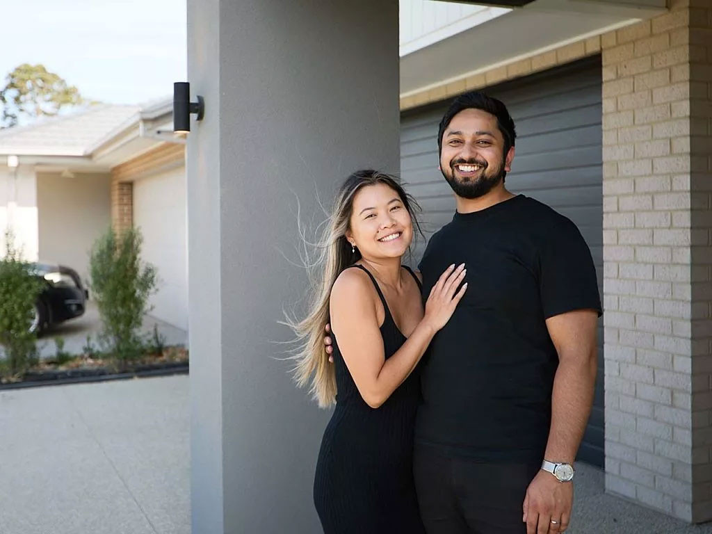 A photograph of the couple, Lauren and David, smiling in front of the closed garage.