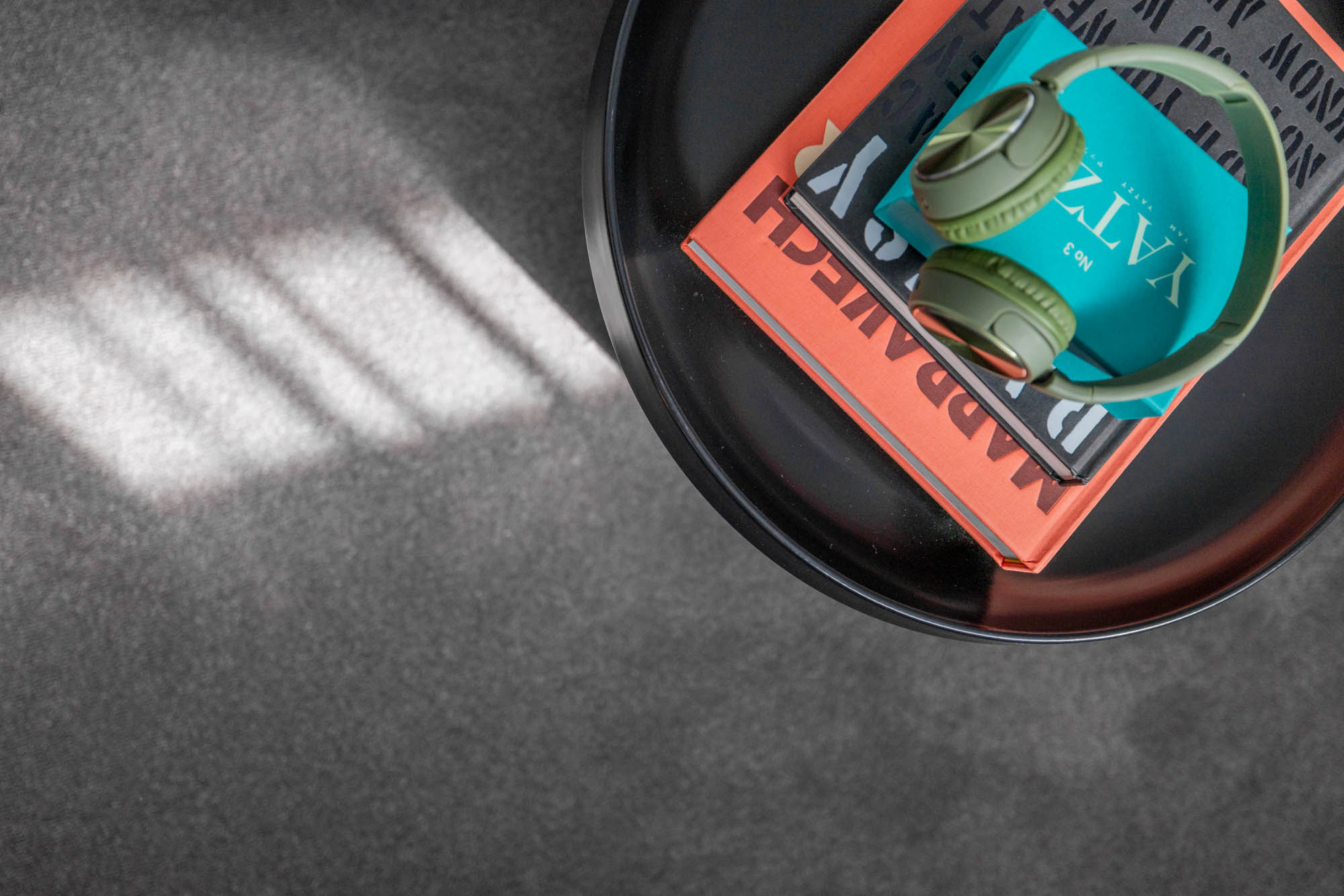 A close-up image of a carpet flooring with books and a headphone on top of a small side table as part of Simonds Berwick 38.