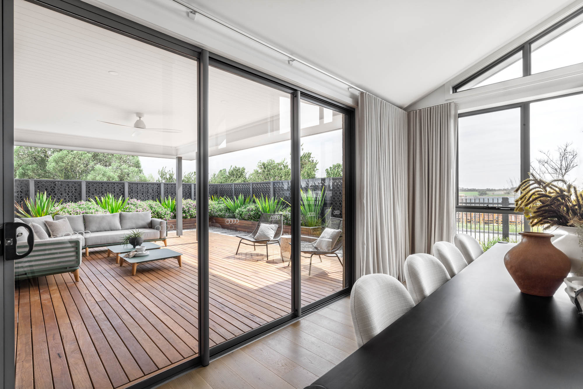 An image of a dining room facing towards an alfresco setting with long sliding windows and wooden floors as part of Simonds Hampstead 32.