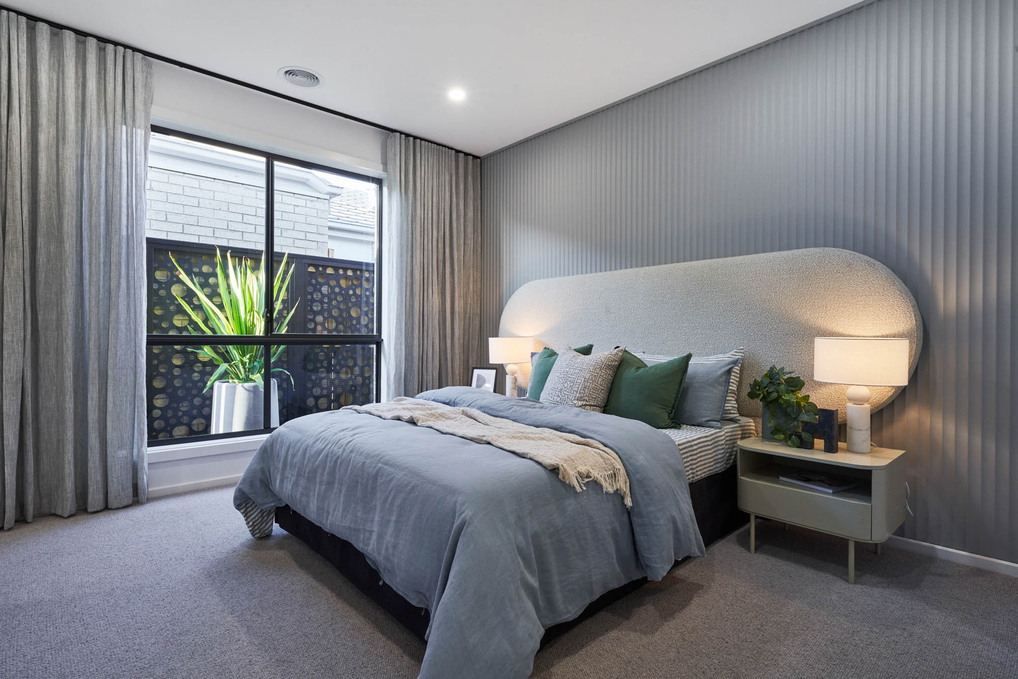 An interior image of a cozy bedroom with large sliding windows and carpet floor as part of Simonds Fairlight 27 home design.