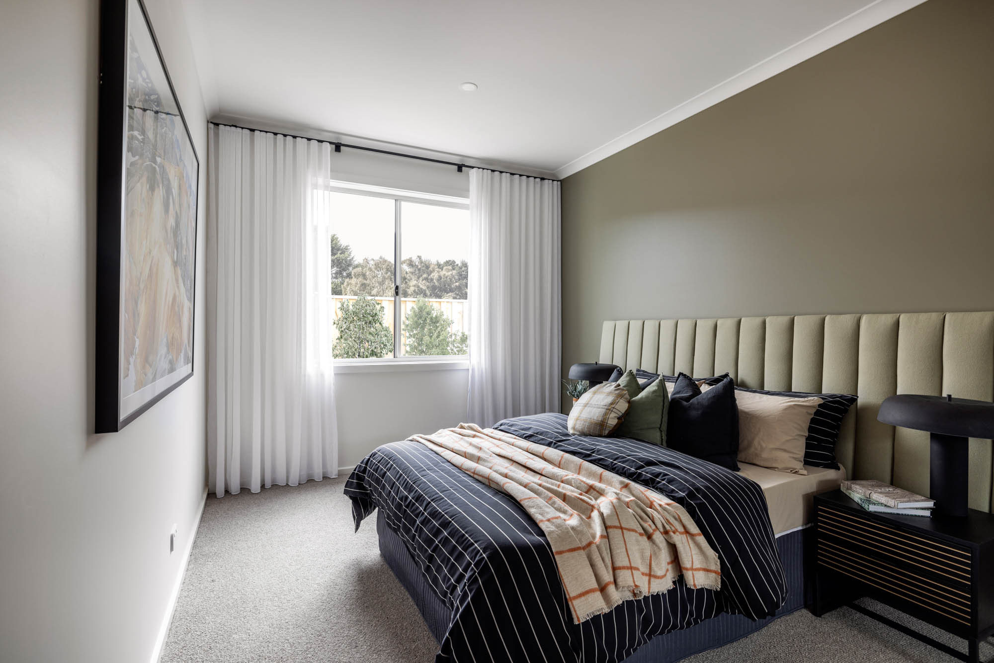 photo of a guest bedroom dark green paint on the feature wall and a dark green bedhead with light grey carpeting in the Simonds Nowra 26 home design in Gisborne